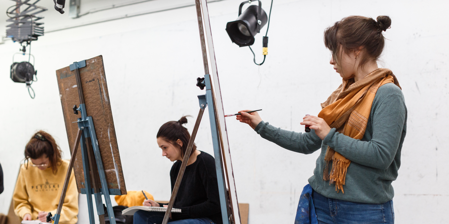 A student paints in an art classroom.