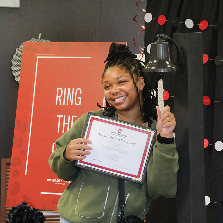 Student ringing a bell and holding a certificate