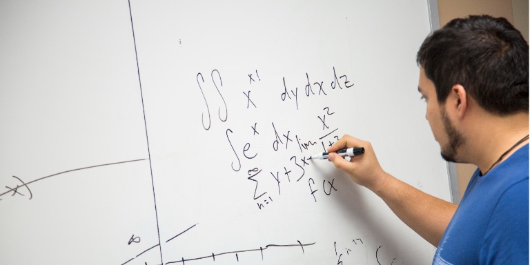 A student solving an equation on the board