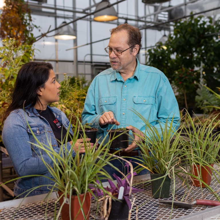 A student with a professor around plants