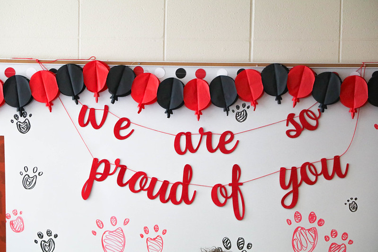 A decoration on a whiteboard that says "We are so proud of you".