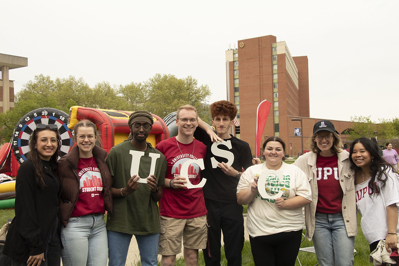 A group of students standing and smiling at the camera. The four in the middle are holding letters that spell UCSC.